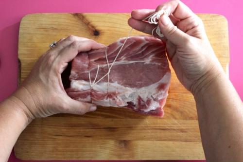 con la parte lunga dello spago iniziate a legare la carne, passatelo sotto ritornate sopra e infilatelo sotto